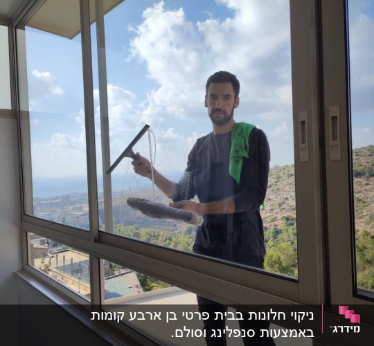 אדם מנקה חלון עם מגב ובד ירוק
